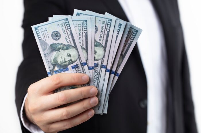 A hand of a businessman holding stack of hundred dollar bills.