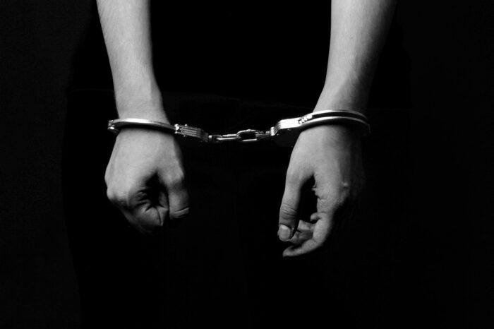 Black-and-white image of handcuffed hands, representing the New Jersey Department of Corrections IDEA violations prison education class action settlement.
