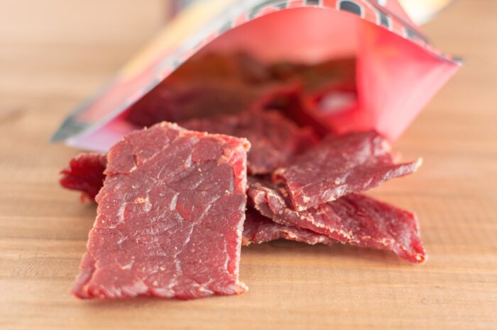 Beef jerky pieces on wooden background.