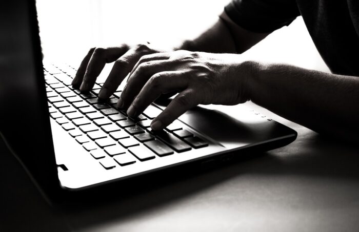 Hands on laptop hacking concept - herff jones data breach - herff jones lawsuit - fraudulent charges