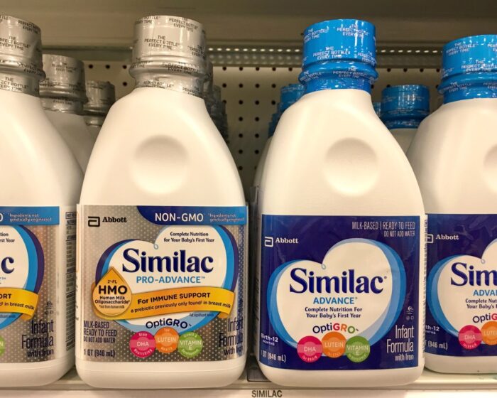 Grocery store shelf with bottles of Similac brand infant formula.