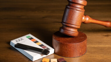 Juul e-cigarette or nicotine vapor dispenser box with Judge's gavel for lawsuit.
