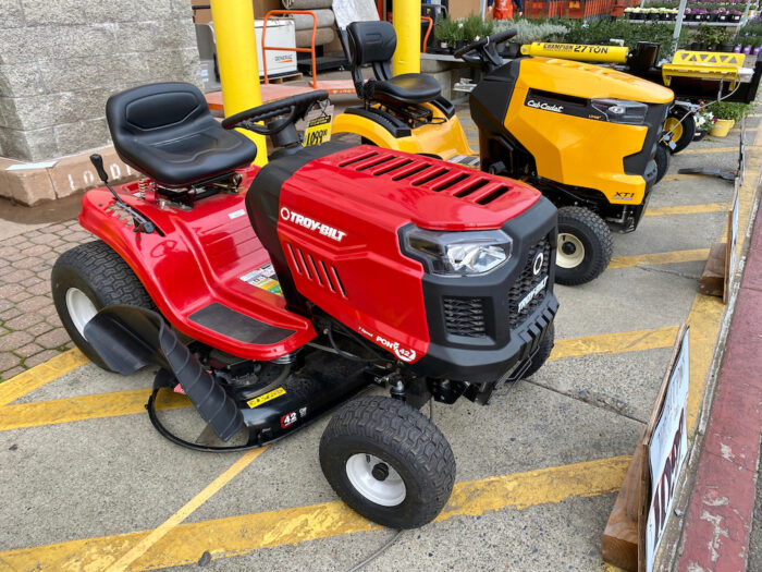 Two brands of ride-on lawn mowers for sale right outside of Home Depot home improvement store.