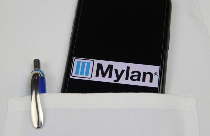 Close up of mobile phone screen with logo lettering of Mylan pharmaceutical company in pocket of white doctors coat
