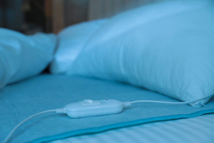 Bed with electric heating pad indoors at night.