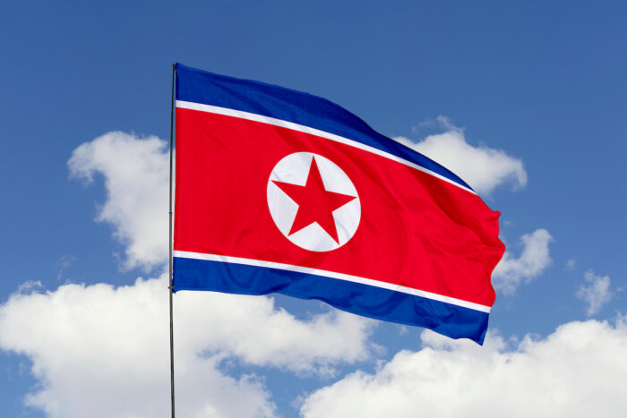 North Korea flag isolated on the blue sky with clipping path. close up waving flag of North Korea.