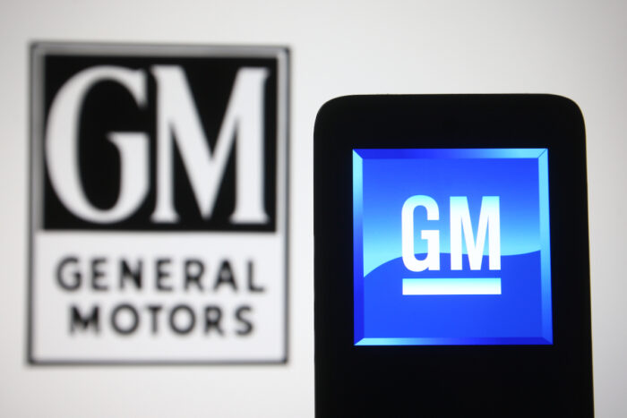 In this photo illustration General Motors Company (GM) logo is seen on a mobile phone and a computer screen.