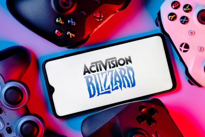 A smartphone with the Activision Blizzard logo on the screen surrounded by gamepads.