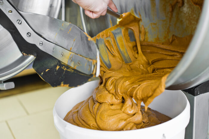 Photo of freshly mixed peanut butter being poured in a bowl. 