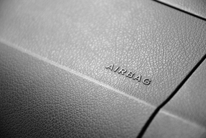 Photo of the word AIRBAG embossed on the dashboard of a car - air bag inflator