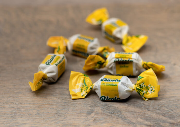 Ricola brand natural herbal cough suppressants scattered on the wooden surface.