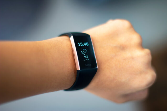 Woman monitoring her heart beat with a fitbit charge 3 activity tracker wearable device on her wrist also known as fitness tracker.