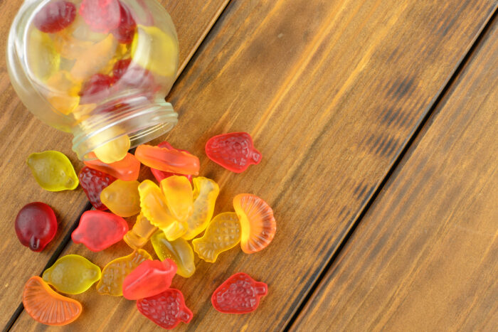 Colored gummy fruit candy spilled, on a brown wooden table.