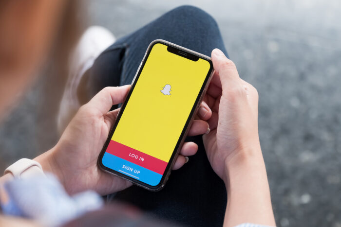 Snapchat application icon on Apple iPhone X smartphone screen close-up in woman hands - Snap class action