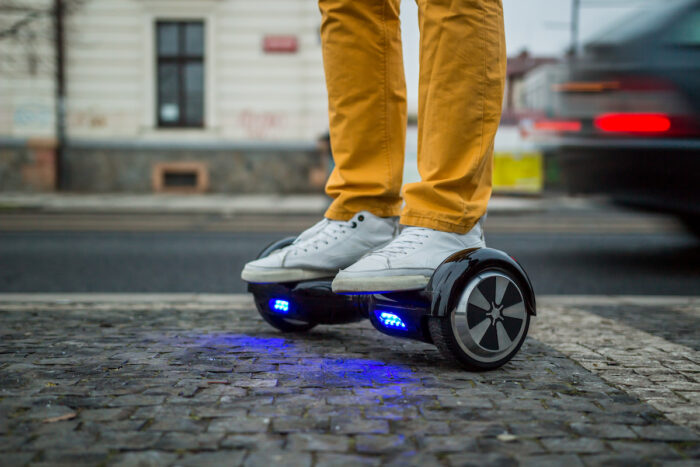 Photo of man using a hoverboard against the background of leaving car.