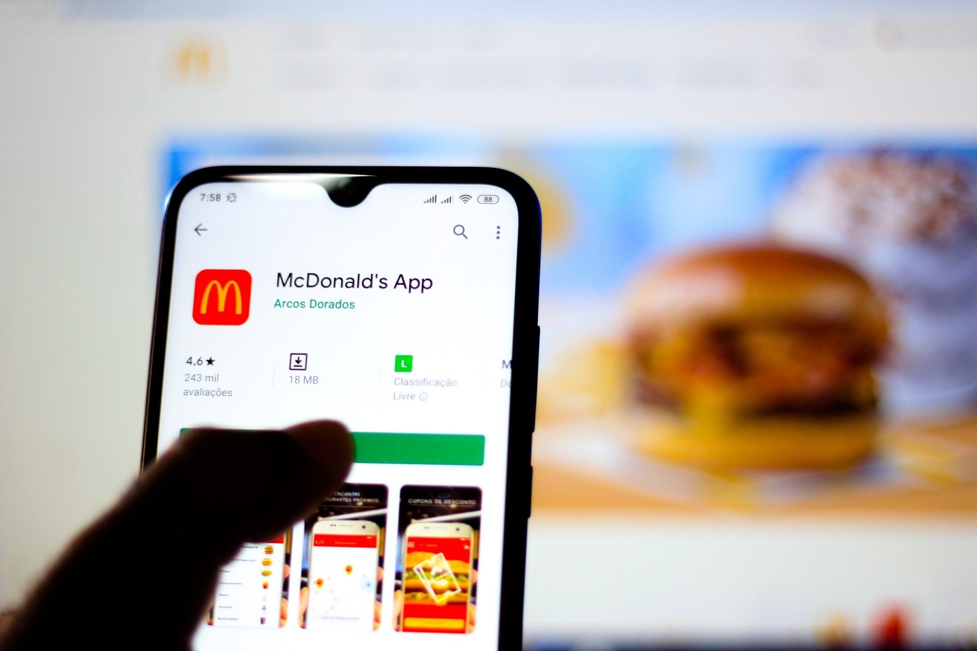 Close up of someone installing the McDonald's app on a smartphone; blurry image of McDonald's food on a screen in the background - mcdonald's lawsuit