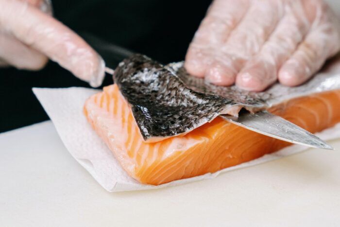 Person cutting skin off a salmon - price-fixing class action
