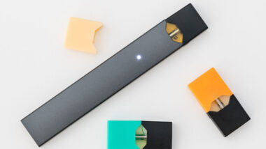 Juul e-cigarette or nicotine vapor stick and JUULpods on white background.