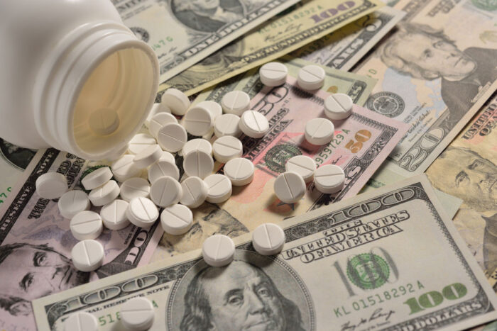 White round medicine tablets spilling from medicine on to money.