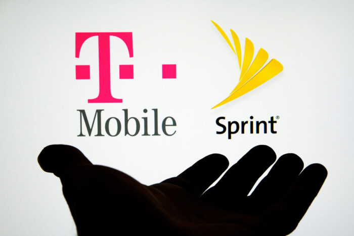 Silhouette of hand and Sprint and T-Mobile logos on the screen behind it - class action, at&t, verizon