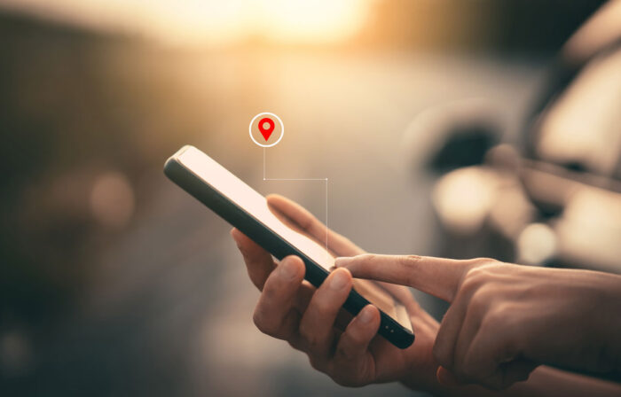 Woman hand using smart phone with navigator location point at street background.