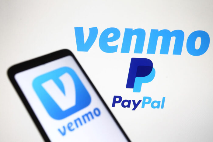 Venmo logo displayed on a smartphone display with Venmo and PayPal logo in the background.