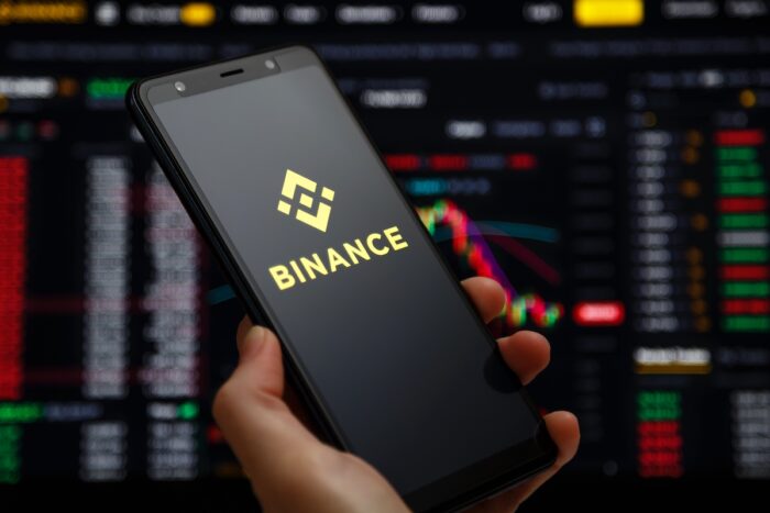 Binance mobile app running at smartphone screen with a trading page at background.