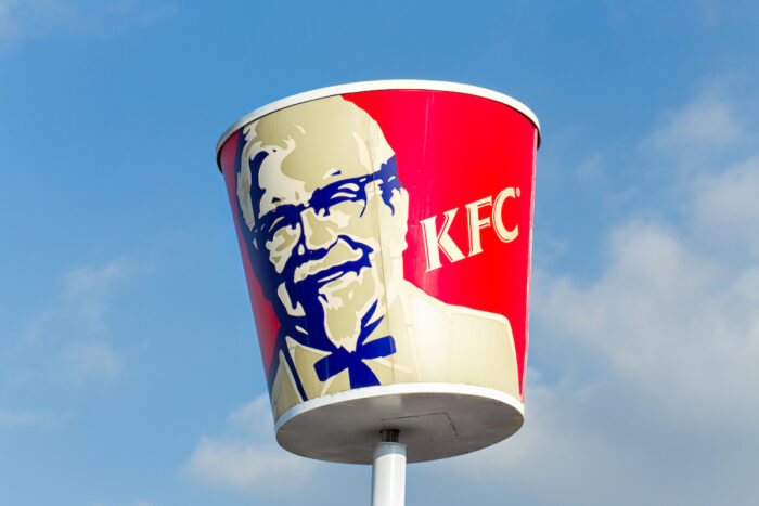 Traditional KFC restaurant sign against a bright blue sky.