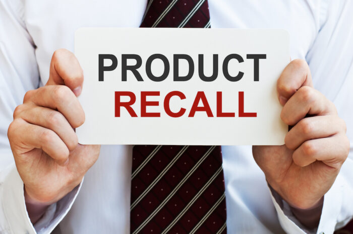 A businessman holding a sign that reads 'product recall' 