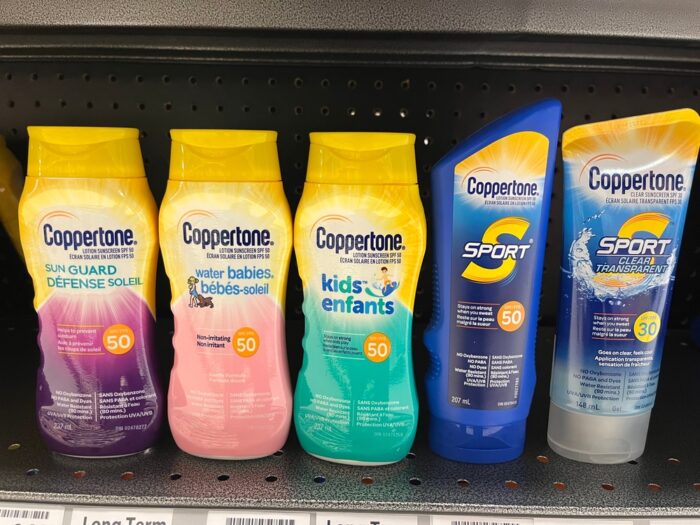 Bottles of various types of Coppertone sunscreen on a pharmacy shelf.