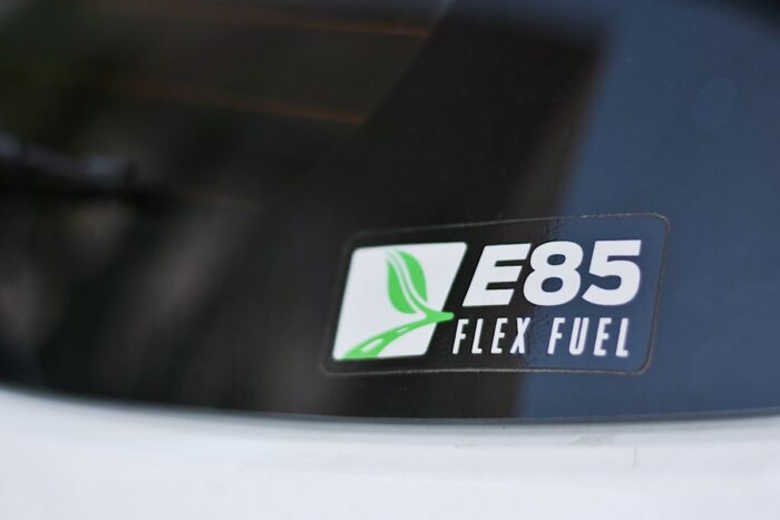 Soft focus image of sticker with logo and wording “E85 FLEX FUEL" stick at rear glass of a car. 