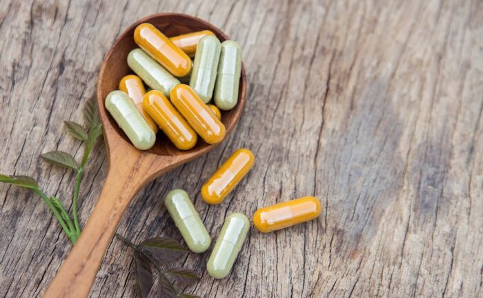 Various laxative capsules on a wooden spoon against a wood background.