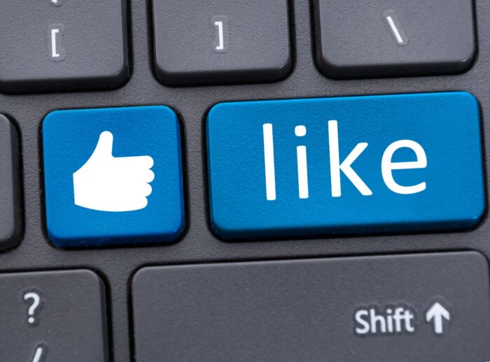 Blue thumbs-up and "like" button on a black computer keyboard - facebook user tracking
