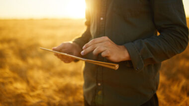 Close up of hands holding a tablet in a rural area.