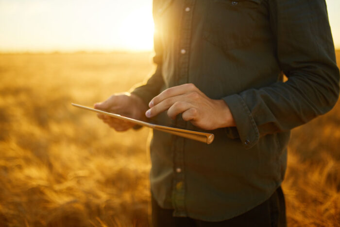 Close up of hands holding a tablet in a rural area.