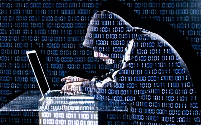 Data breach concept, image of hooded man leaning over laptop - timios data breach class action lawsuit
