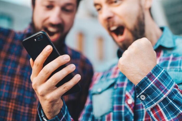 Two friends looking extremely excited getting good news winning a bet in online app - spinx games lawsuit, casino apps