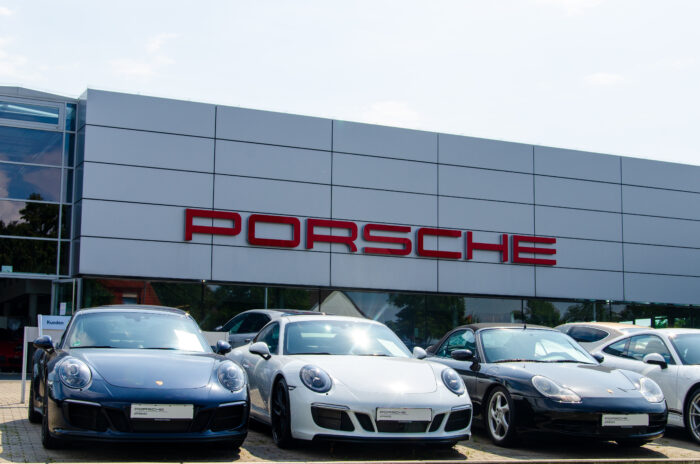 Cars parked next to each other in front of a Porsche dealer - porsche gasoline fuel economy class action lawsuit settlement