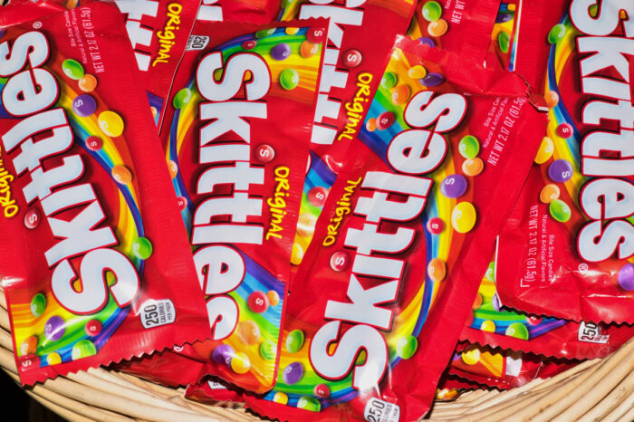 Skittles candy packets scattered loosely in a wicker basket.