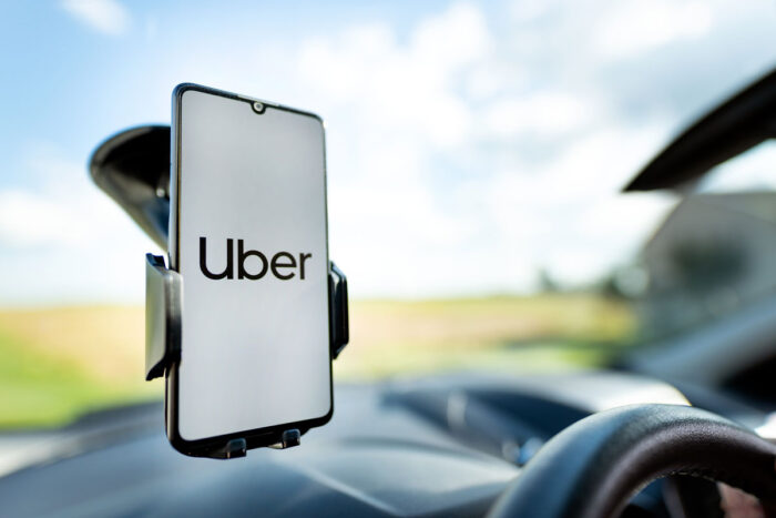 Uber driver holding smartphone in car  - settlement, discrimination, doj