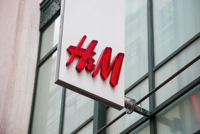 Closeup of H&M sign on modern building facade in the street.