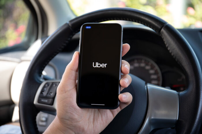 Man hands holding Apple iPhone 11 with application Taxi Uber in the screen.