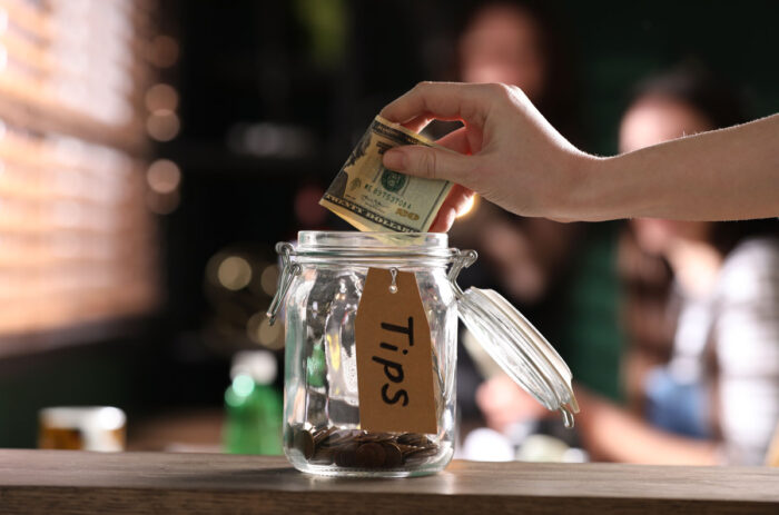Close up of a hand placing cash into a tip jar inside a Starbucks coffee shop.