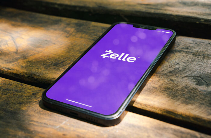 Zelle app on the smartphone screen on the rustic wooden table in the park.