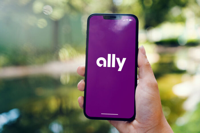 Girl in the park holding a smartphone with Ally financial bank app on the screen.