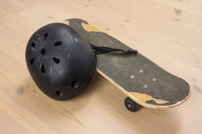 Skateboard and protective helmet on a wooden floor.