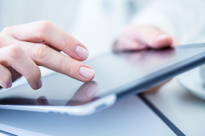 Close-up of female hands touching digital tablet.