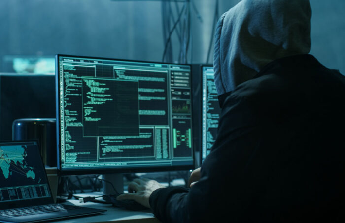 Hacker wearing a hoodie hacking into a network system.