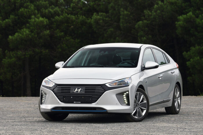 2017 Silver Hyundai Ioniq parked in empty parking lot with tall dark green trees in the background.
