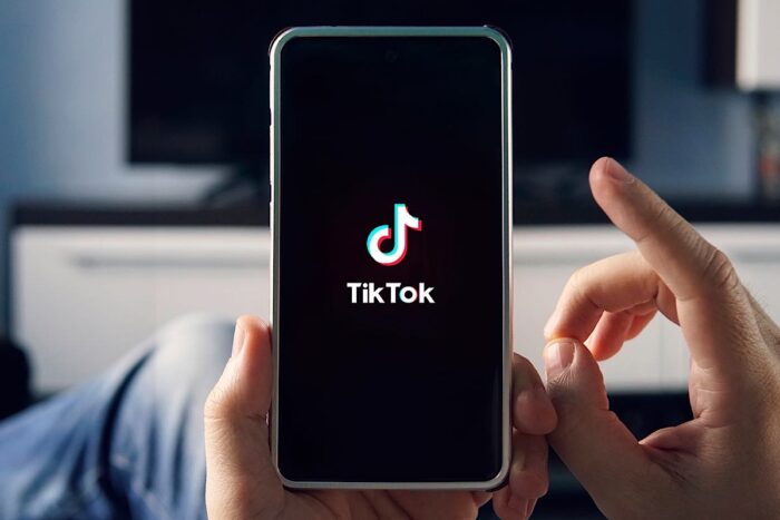 Man holding smartphone with TikTok logo on the screen - meta 